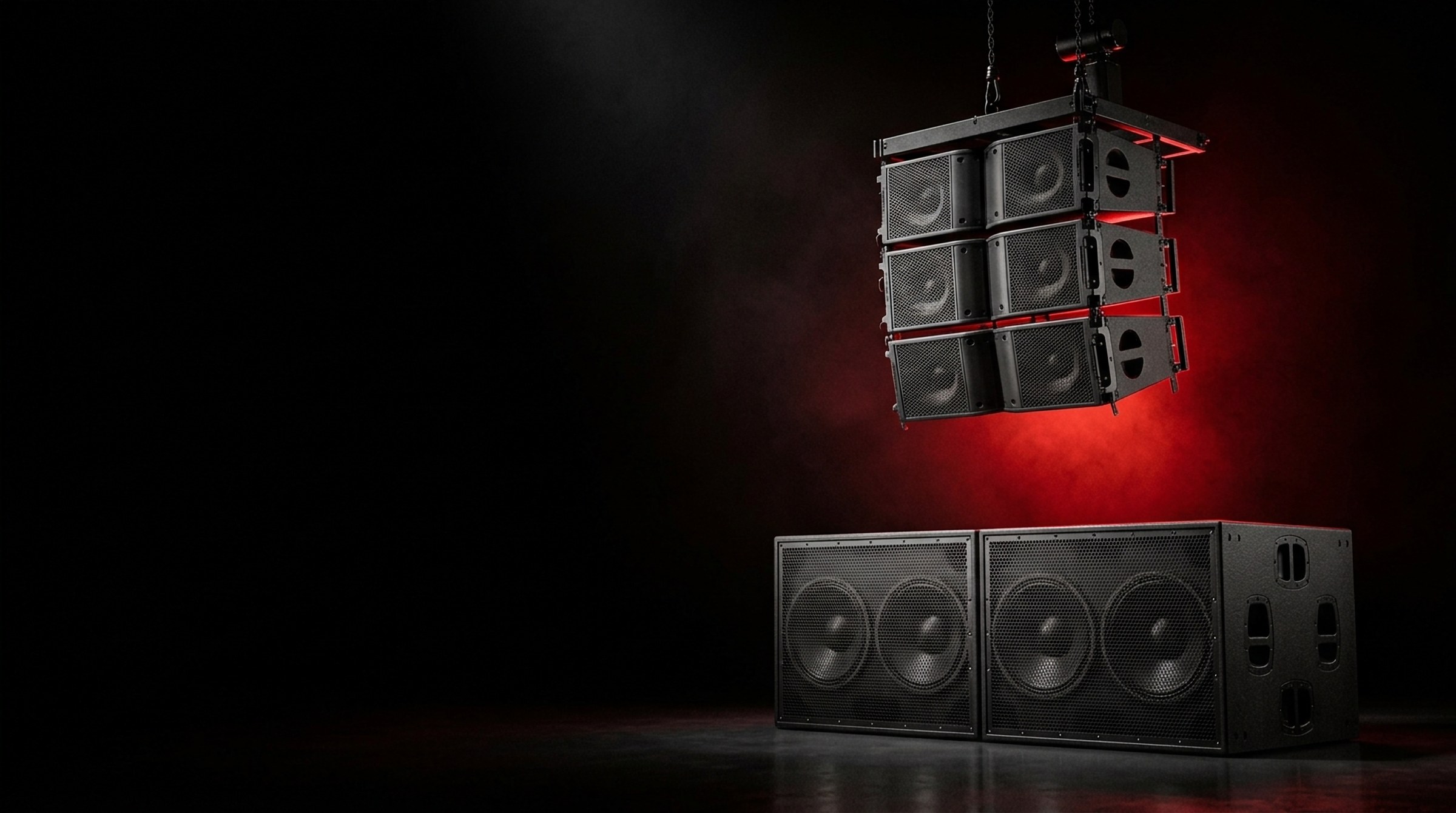 A black line-array speaker stack and two subwoofers lit with red light